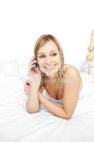 Beautiful woman talking on phone lying on her bed