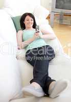 Cheerful woman sending a text lying on a sofa