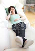 Happy woman talking on phone lying on a sofa