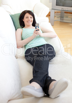 Jolly woman sending a text lying on a sofa