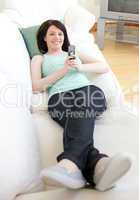 Jolly woman sending a text lying on a sofa