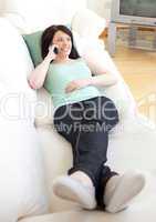 Charming woman talking on phone lying on a sofa