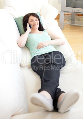 Smiling woman talking on phone lying on a sofa