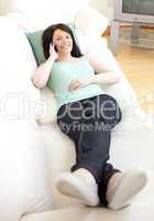 Smiling woman talking on phone lying on a sofa