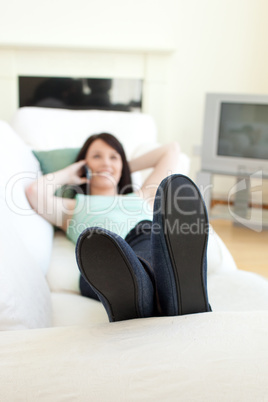 Smiling woman talking on phone lying on a sofa