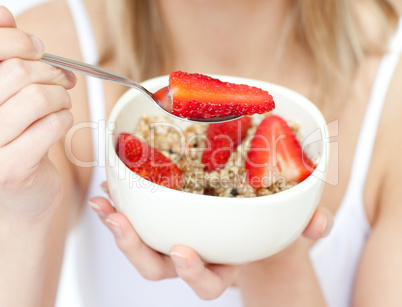 Close-up of a woman eating cereals with strawberries