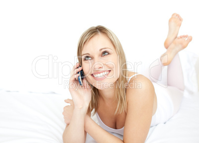 Radiant woman talking on phone lying on her bed