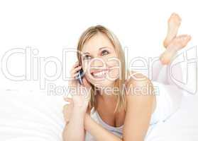 Radiant woman talking on phone lying on her bed