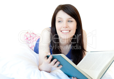 Portrait of a smiling teen girl studying lying on a bed