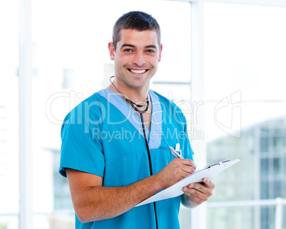 Smiling male doctor making notes on a patient folder
