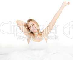 Radiant woman stretching sitting on her bed