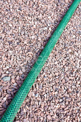 Green garden hose on a gravil path