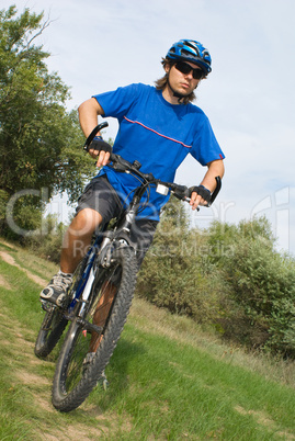 young bicyclist in a blue helmet on nature