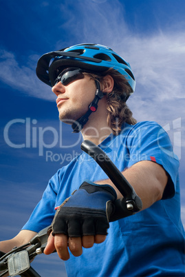 young biker in helmet on a blue sky background
