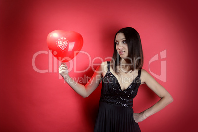 Beautiful girl with a red balloon in the form of heart