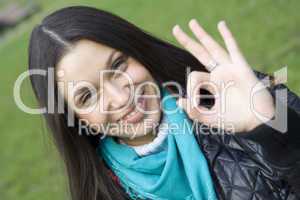 Beautiful girl in a park smiling. Hand sign OK