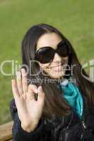 Beautiful girl in a park smiling. Hand sign OK