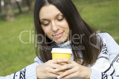 Beautiful girl in a park drinking coffee