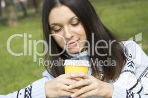 Beautiful girl in a park drinking coffee