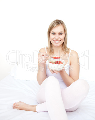 Delighted woman eating cereals with strawberries