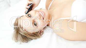Jolly woman talking on phone lying on her bed