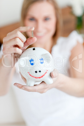 Blond woman saving money in a piggy-bank