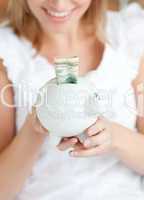 Blond woman saving money in a piggy-bank