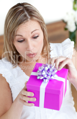 Surprised woman opening a gift sitting on the floor