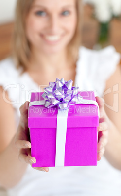 Young woman holding a present sitting on the floor
