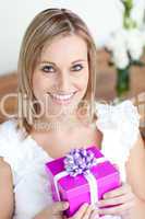 Charming young woman holding a present sitting on the floor
