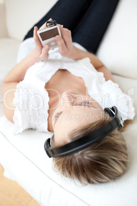 Caucasian young woman listening music lying on a sofa