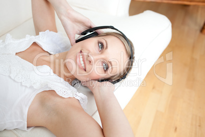 Bright young woman listening music lying on a sofa