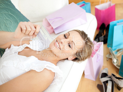 Charming woman holding a credit card surrounded with shopping ba