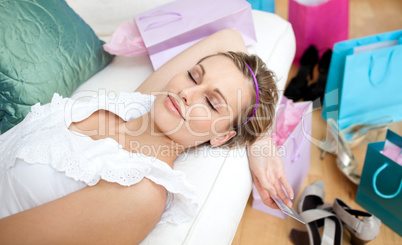 Happy woman relaxing after shopping surrounded with shopping bag