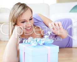 Attractive blond woman holding a present lying on the floor