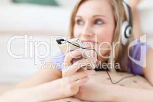 Blond woman listening music lying on the floor