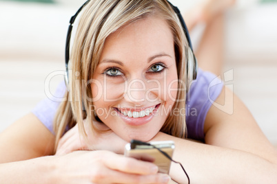 Happy woman listening music lying on the floor