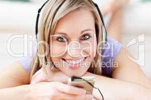 Happy woman listening music lying on the floor