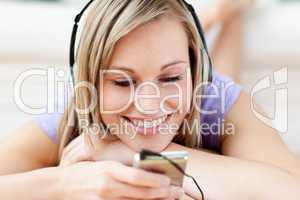 Cheerful woman listening music lying on the floor
