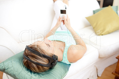 Portrait of a blond woman listening music lying on a sofa