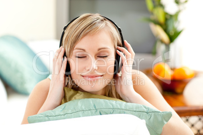 Relaxed blond woman listening music lying on a sofa