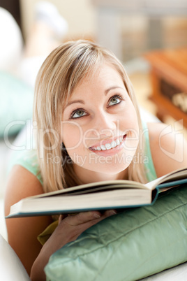 Attractive woman lying on a sofa reading a book