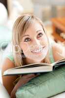 Attractive woman lying on a sofa reading a book