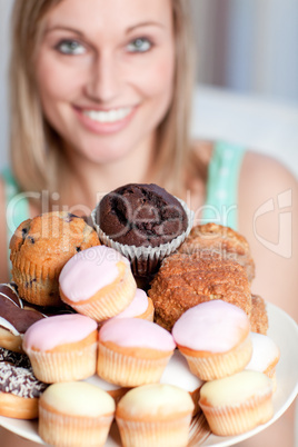 Happy woman holding a plate of cakes