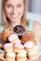 Happy woman holding a plate of cakes