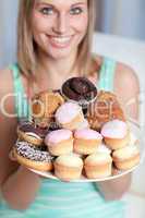 Smiling woman holding a plate of cakes