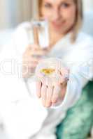 Sick woman holding a glass of water and pills