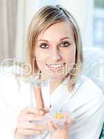 Sick caucasian woman holding a glass of water and pills