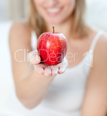 Close-up of a blond woman showing an apple
