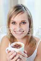 Portrait of a happy woman drinking a coffee sitting on a sofa